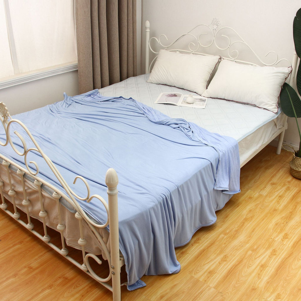 Blue lightweight cooling blanket styled on a bed